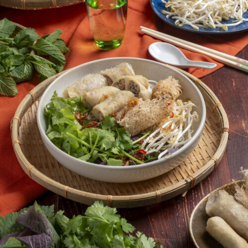 Vietnamese vermicelli noodle salad topped with crispy pork spring rolls and fresh herbs